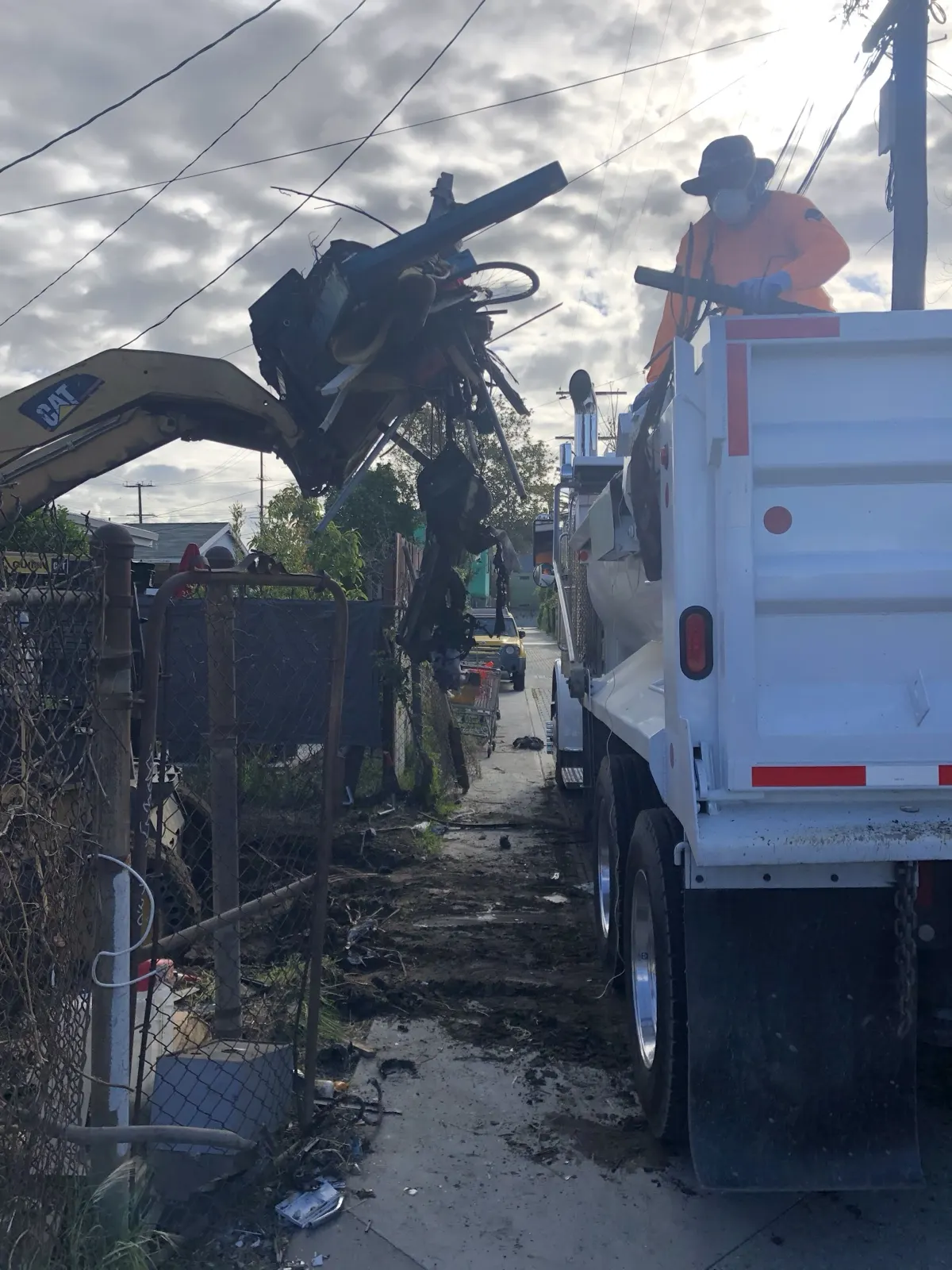 Loading debris into one of our dump trucks from a narrow alley