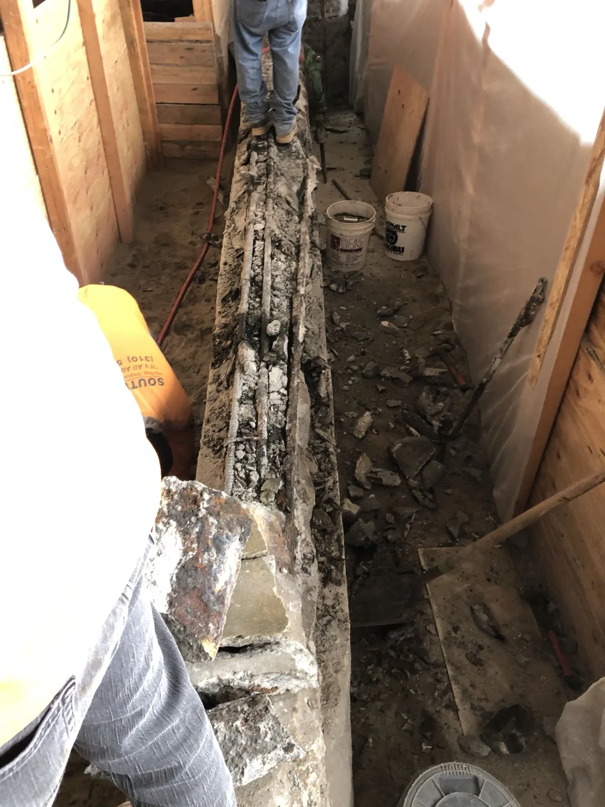 Interior demolition with the slab cut open along a foundation line inside a framed building