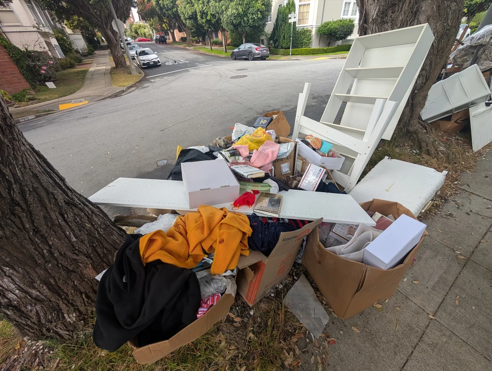 Boxes, shelves and household items piled at a curb corner for pickup