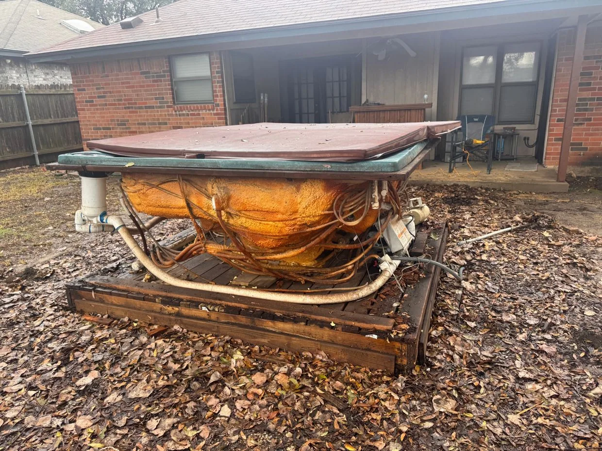 Weathered hot tub with its cover on, waiting for removal in a backyard